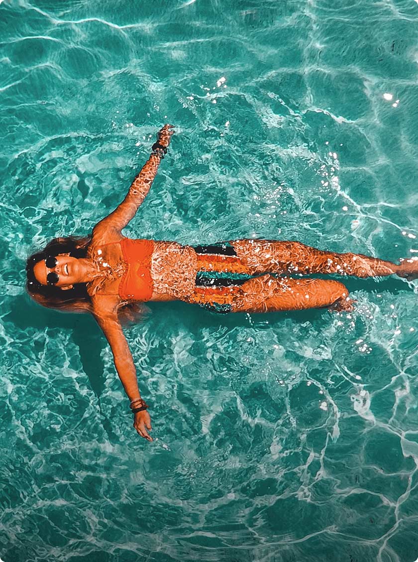 Woman wearing sunglasses floating in an inground pool.