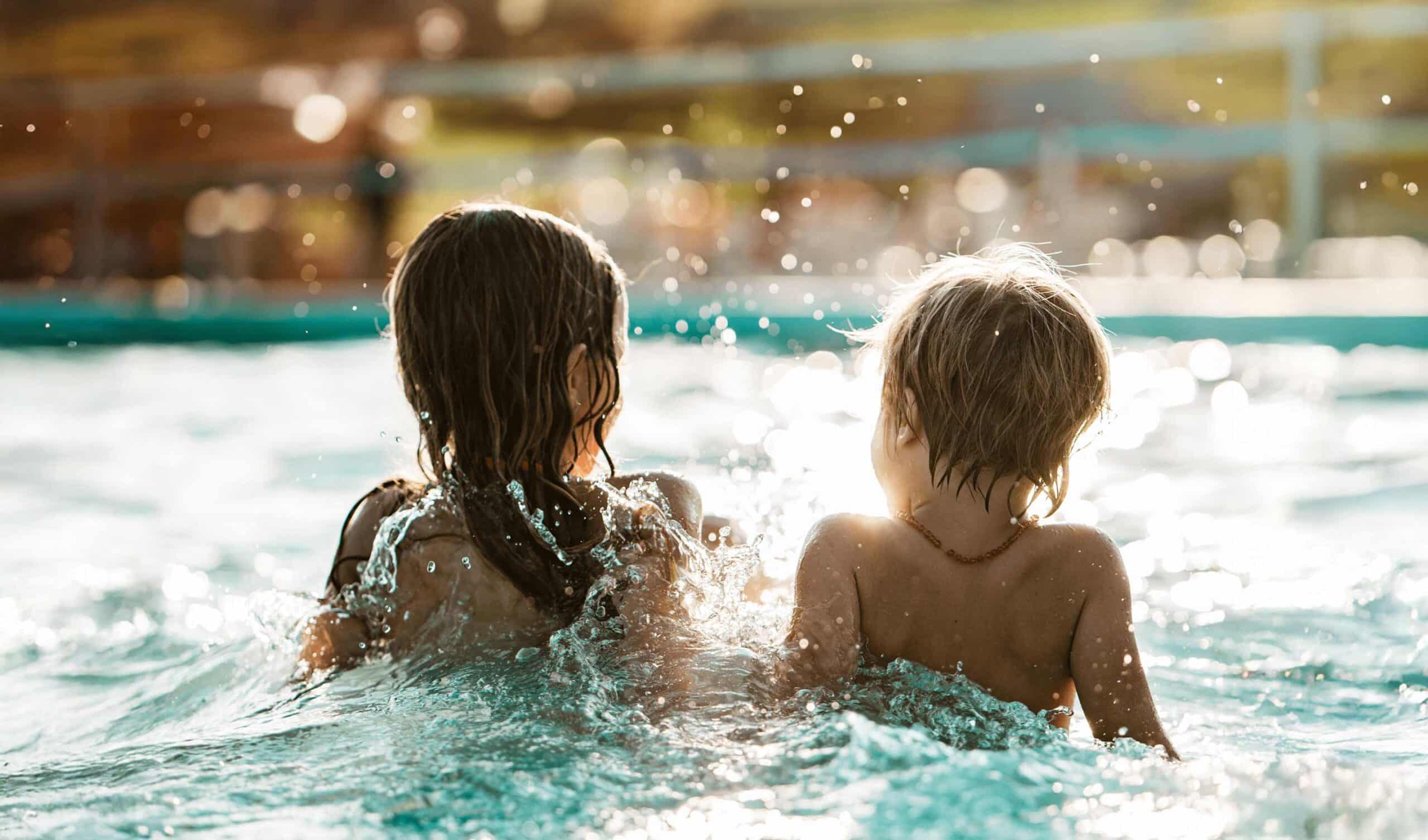 Two children playing in an inground pool.