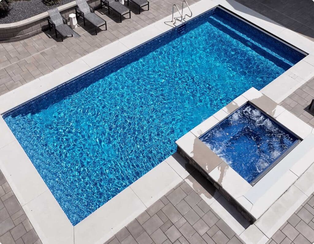 Overview of a vinyl liner pool installed in a residential setting, with stone pavers.