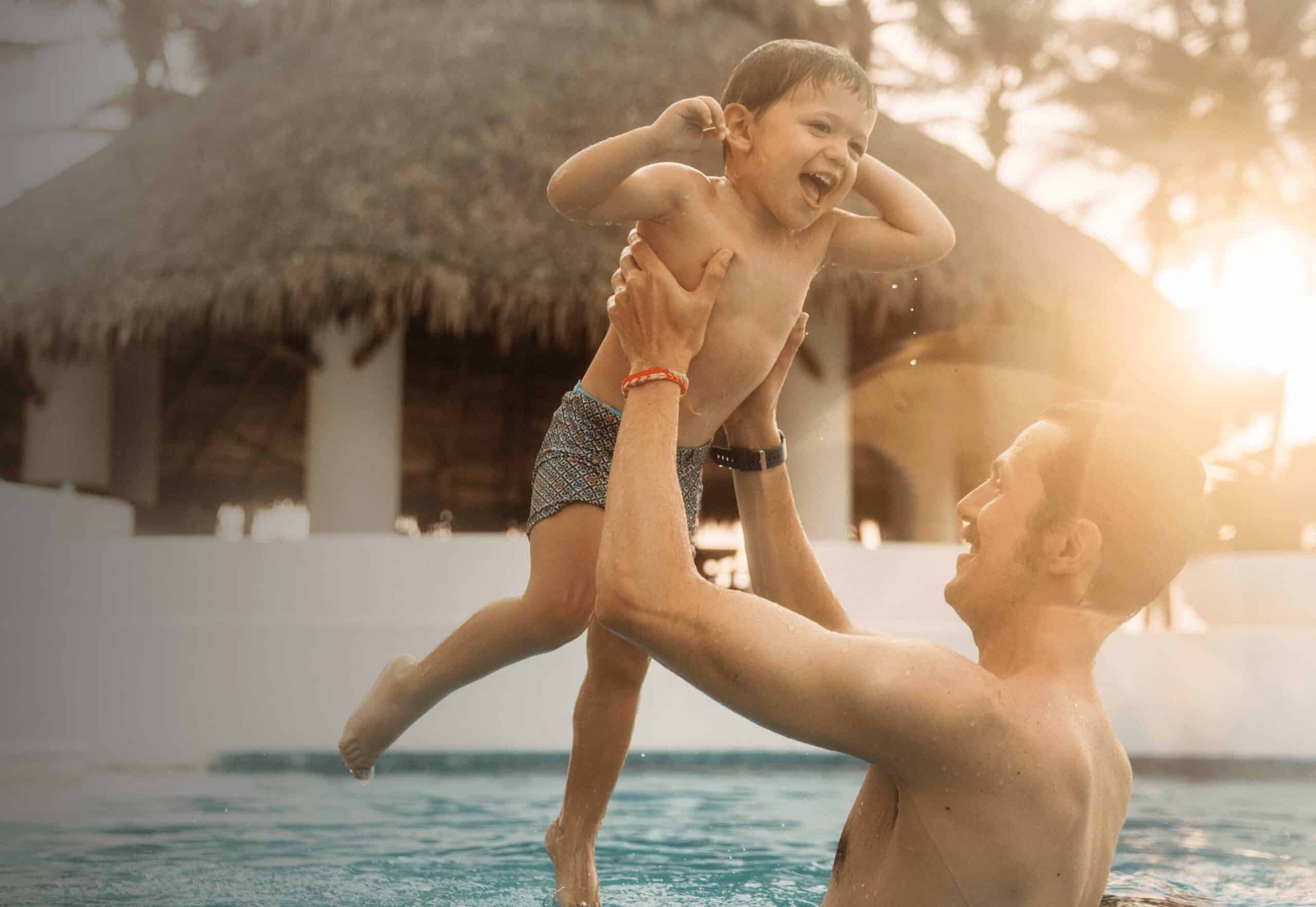 Parent holding their child in an inground pool.