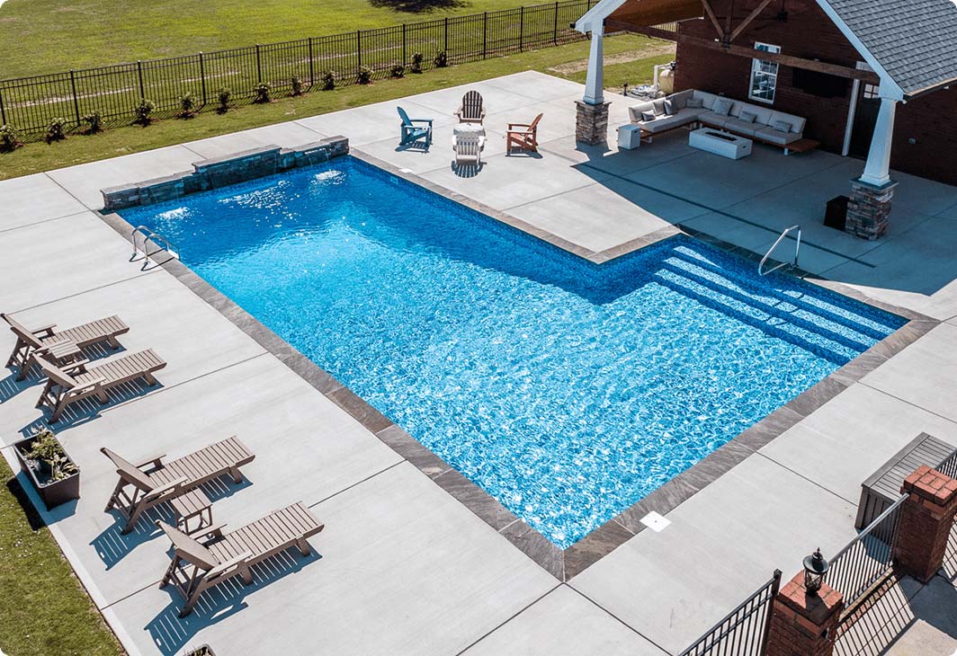 L shape vinyl liner pool with light blue interior and backyard landscaping.