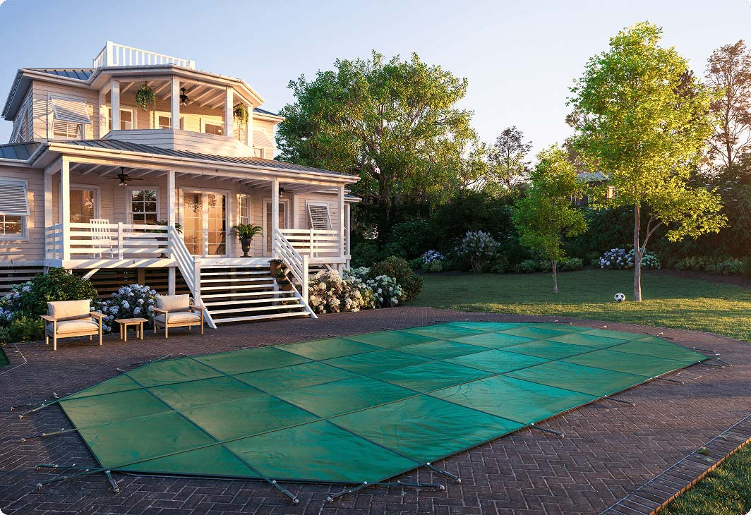 Winter safety cover stretched across a backyard pool.