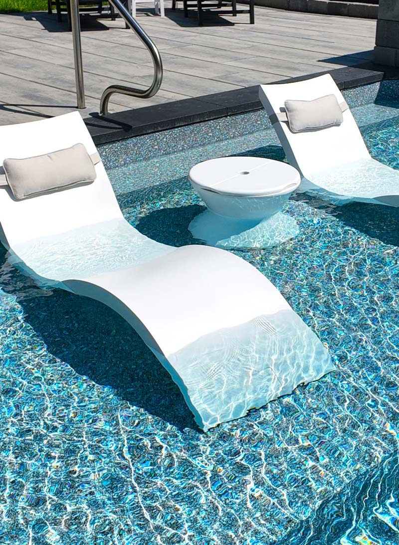 Large tanning ledge with lounge chairs in shallow end of pool