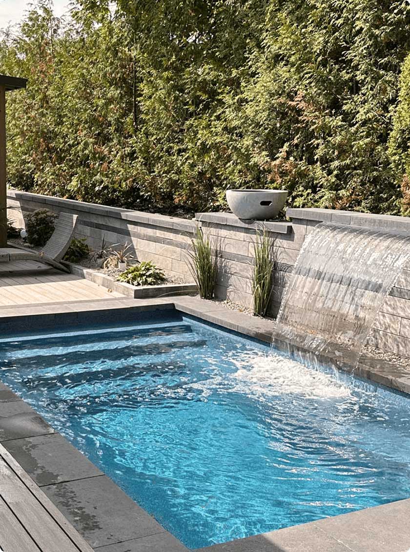 Tranquil backyard with stone tiles, inground plunge pool and water features