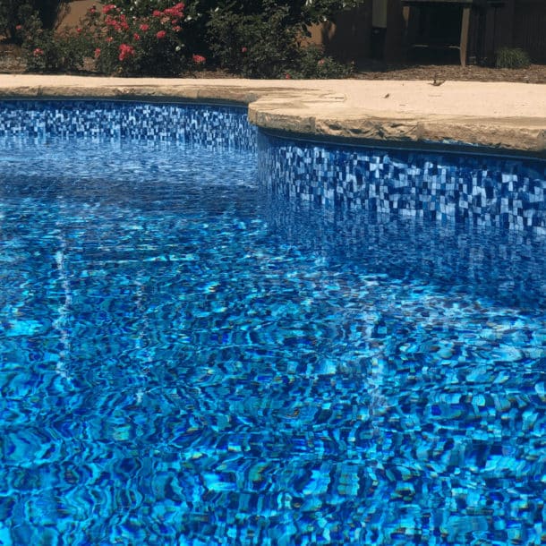 Sparkling inground pool with a shimmering disco pearl liner pattern, reflecting the bright sunlight.