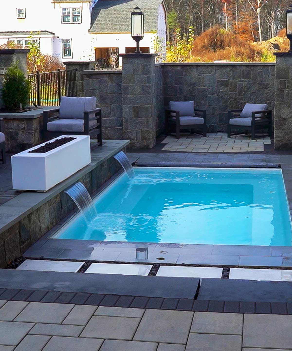 Peaceful cozy backyard with stone walls, inground plunge pool and water features