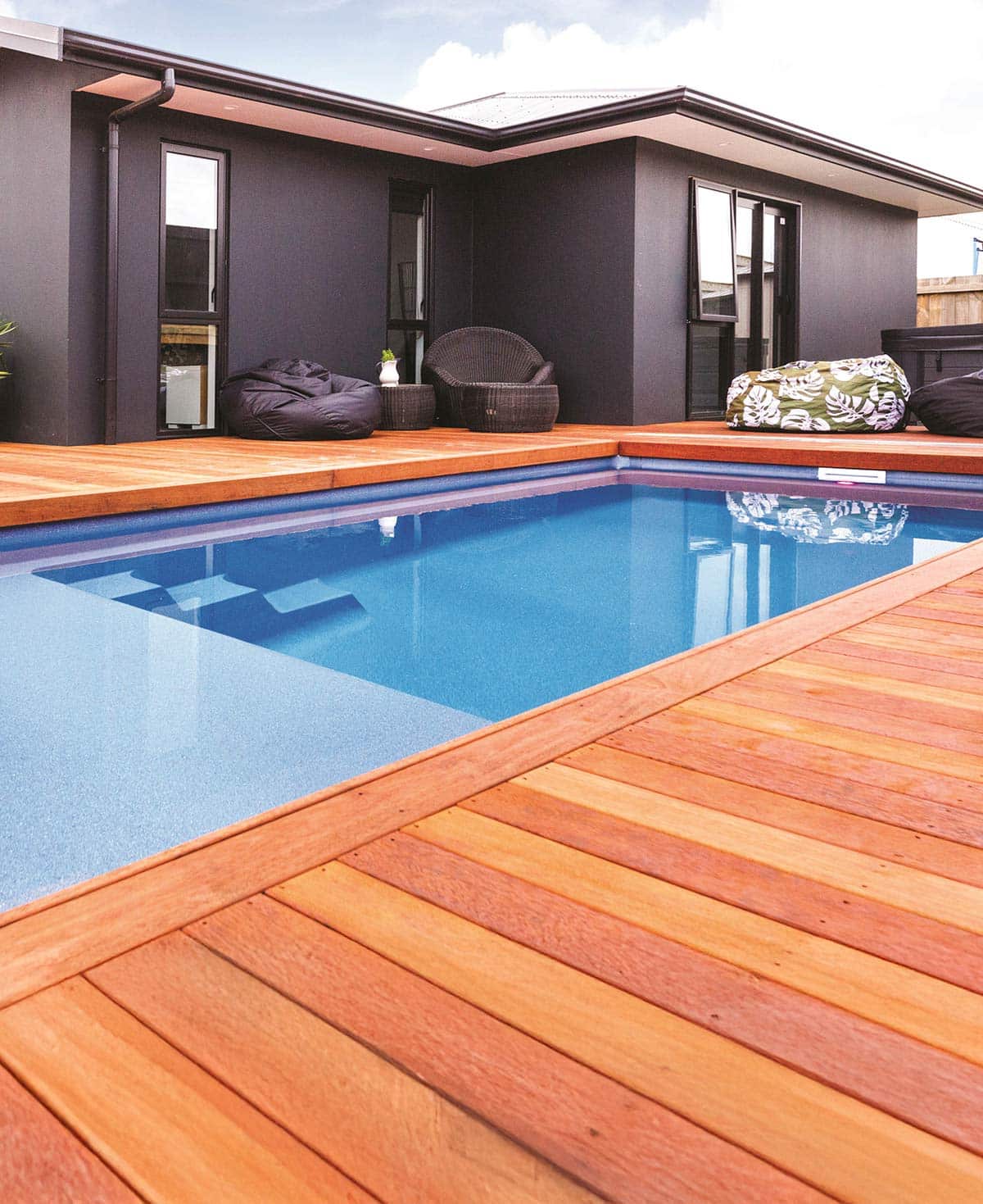 dark one story home with beautiful wood decking and inground plunge pool